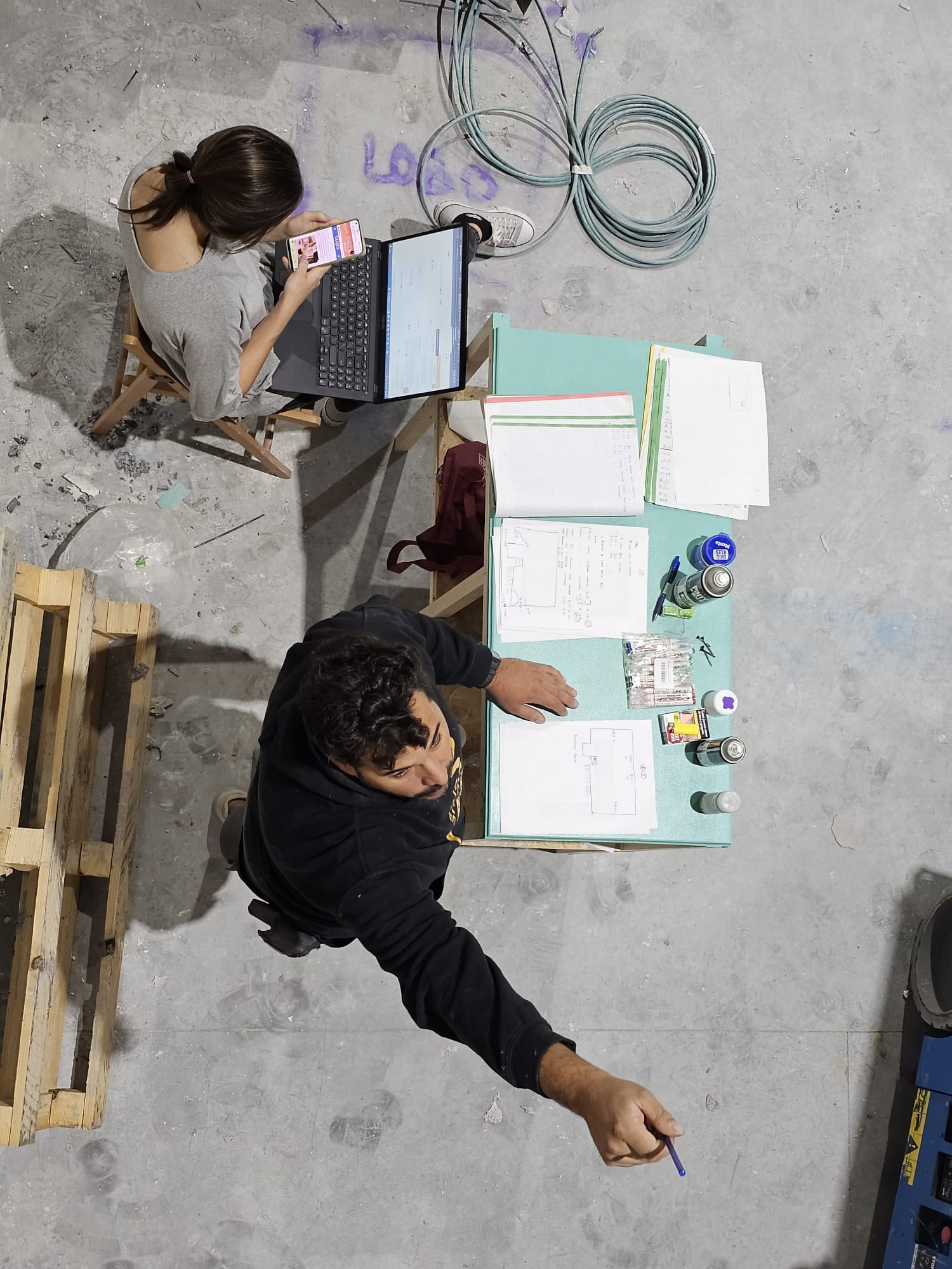 Vista cenital de dos miembros del equipo revisando planos durante la construcción